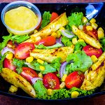A plate of honey mustard chicken salad with fresh greens and cherry tomatoes